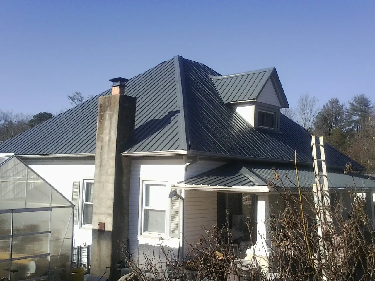 Dark blue standing seam metal roof on a white farmhouse with dormer — Slate & Tile Roof Repair by Roofing Brothers in Toccoa
