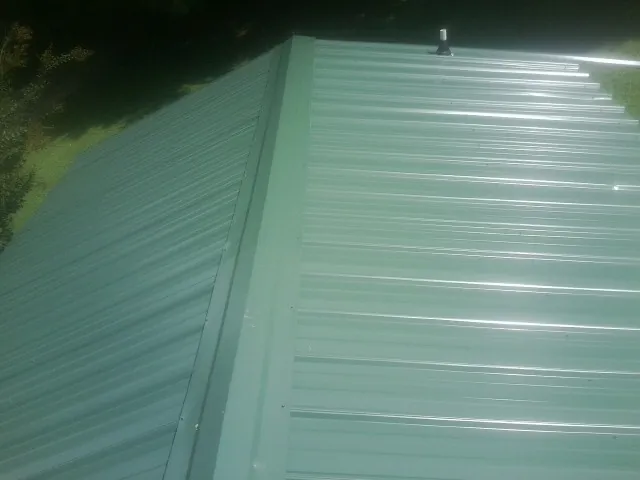 New green metal panels meeting at the ridge of a roof — Flat Roof Repair work by our crew in Toccoa