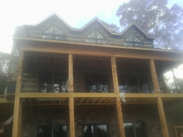 Dormers and porch framing on a large log home under construction — Roof Coating work by our crew in Toccoa