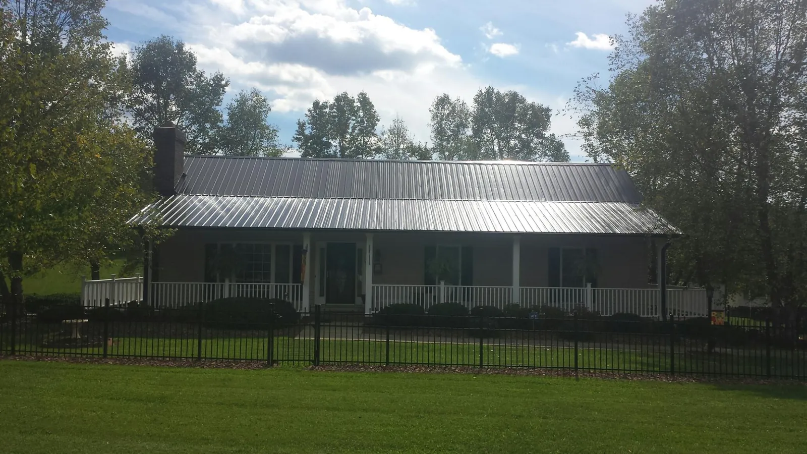 Gray metal roof on a brick ranch with a full width front porch — Gutter Guard Installation work by our crew in Toccoa