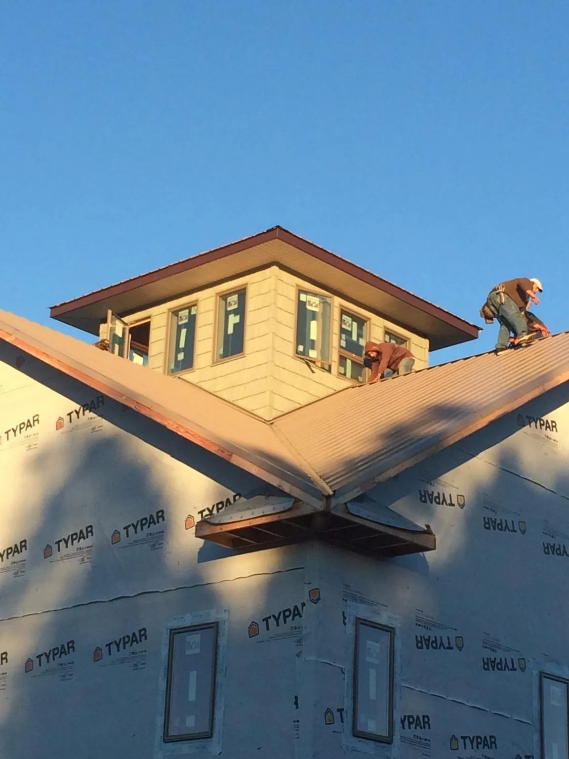 Roofers working around a rooftop cupola on a new metal roof at sunset — Roof Waterproofing in Toccoa by Roofing Brothers